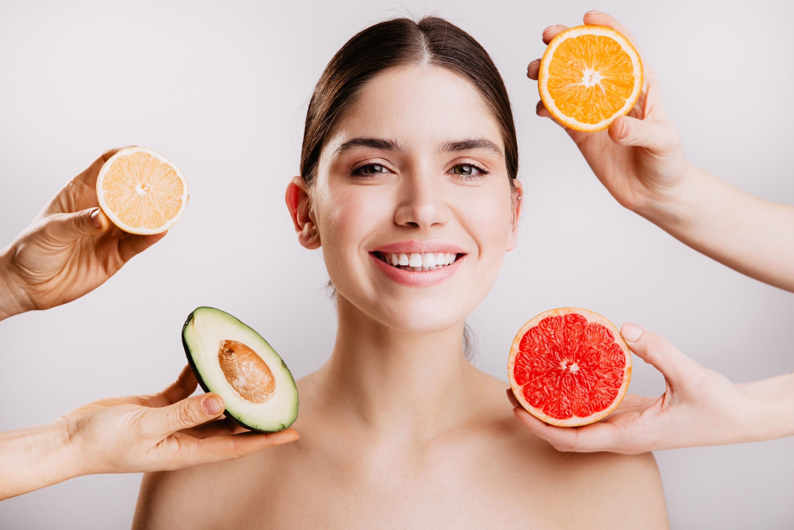 Healthy beautiful radiant skin of woman without makeup. Portrait of girl smiling against background of fruits